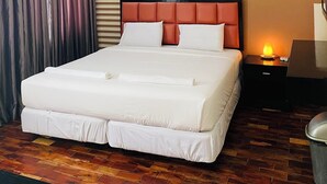 A hotel room with a large bed, a nightstand with a lamp, and a wall-mounted air conditioner. - Arabelle Suites (Tagbilaran)