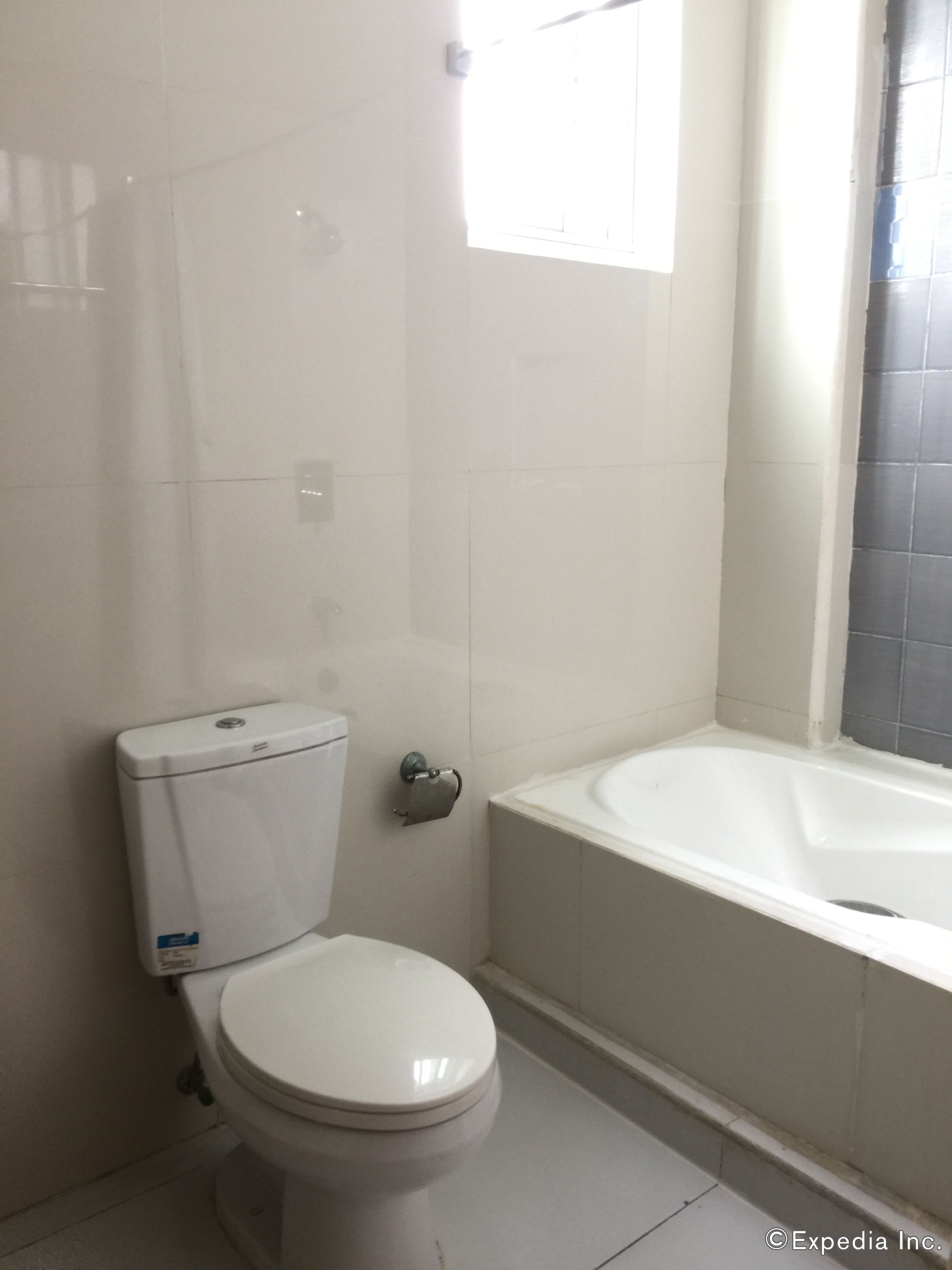 A bathroom with a toilet, a bathtub, and a window.