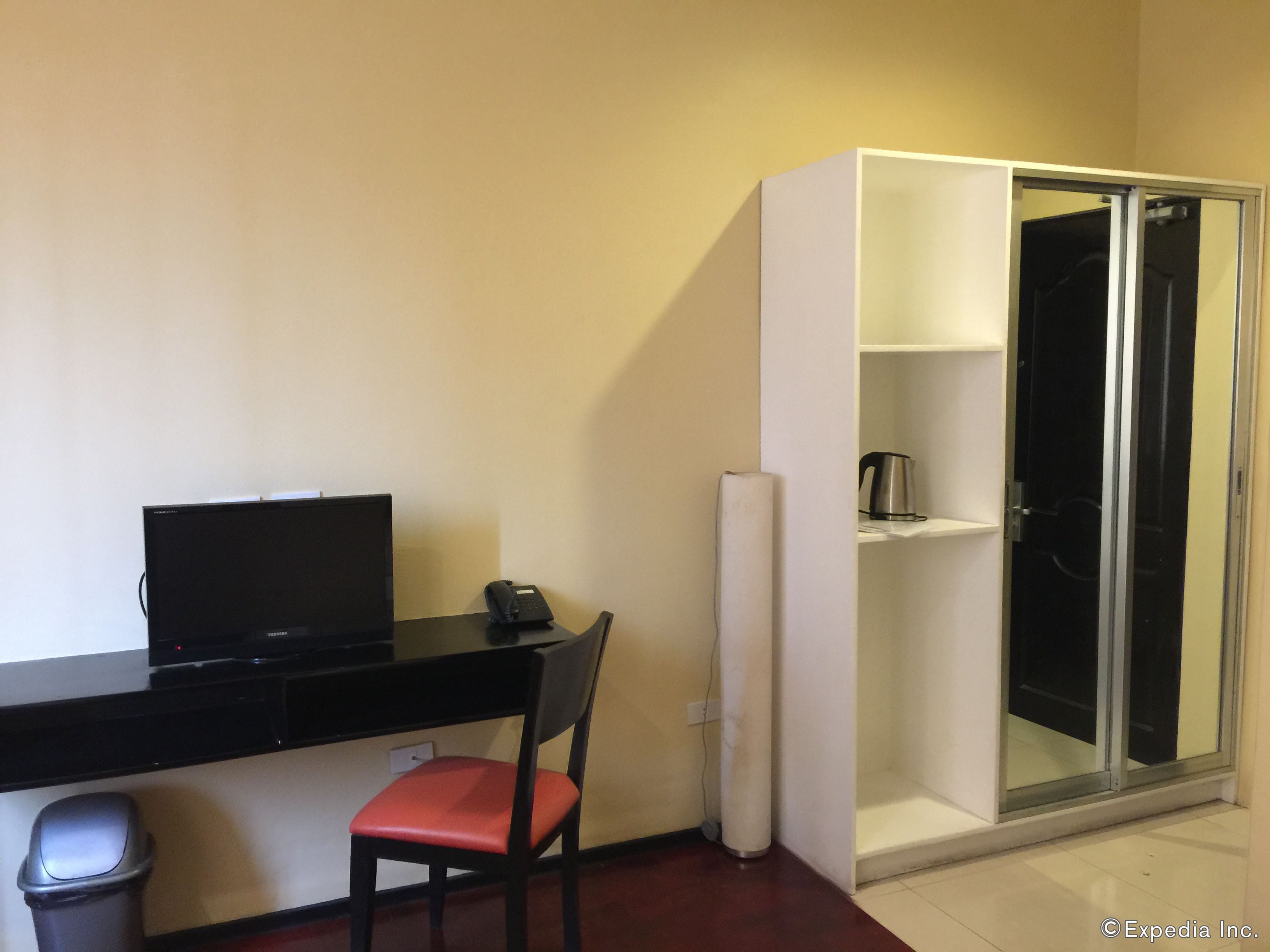 A compact room with a desk, chair, and a sliding glass door closet.