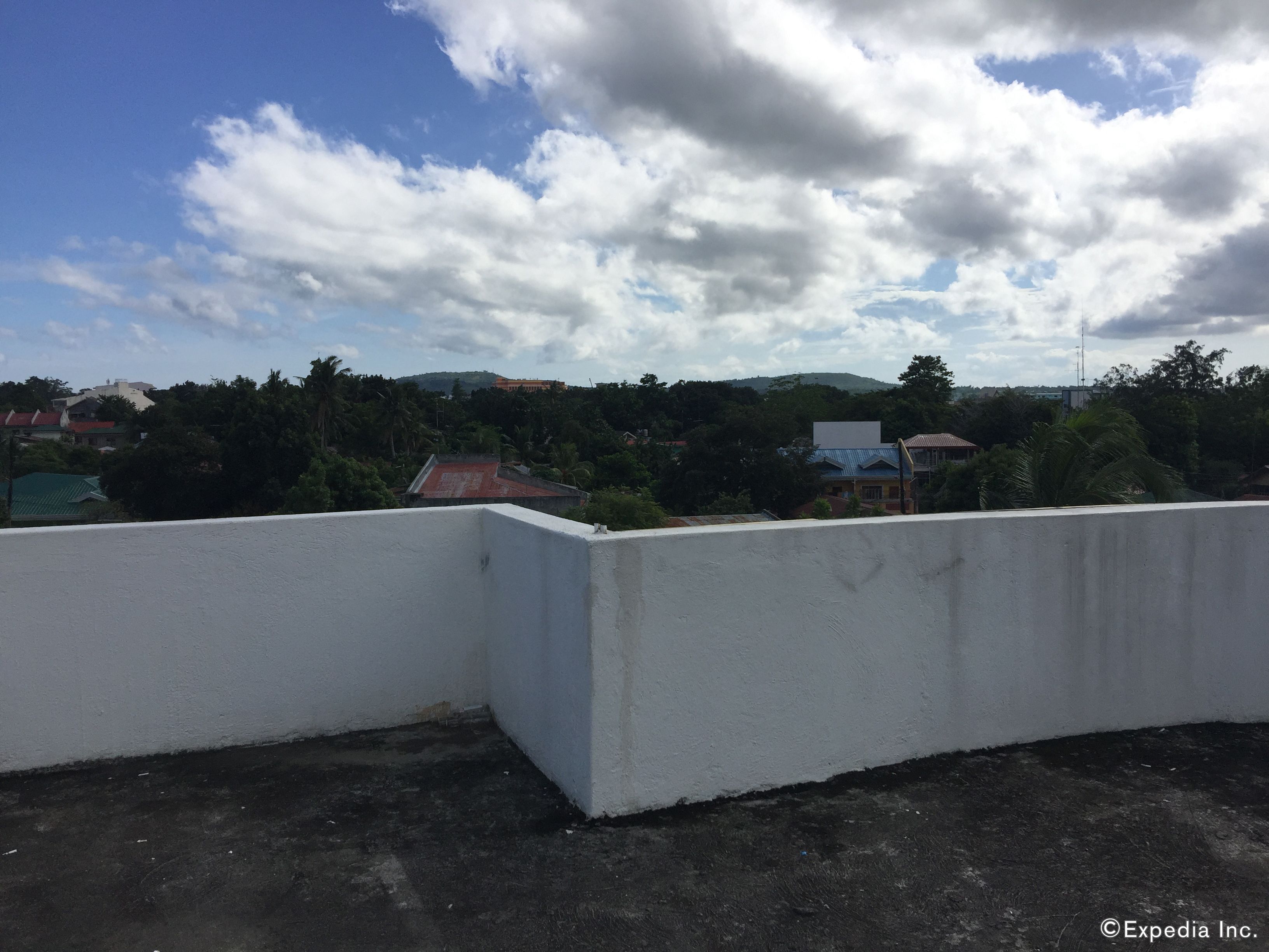 Un toit-terrasse avec un mur blanc et une vue sur une ville avec des maisons et des arbres.