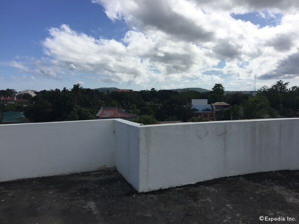 Una terraza con un muro blanco y vistas a un pueblo con casas y árboles.