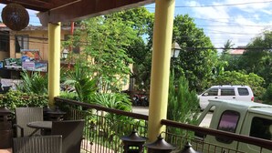 A covered outdoor seating area with wicker chairs and tables, surrounded by metal lanterns, under a wooden roof structure. - Arabelle Suites (Tagbilaran)