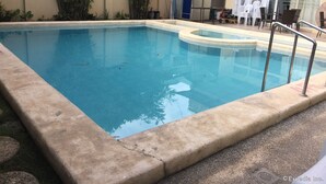 A rectangular pool with a concrete edge, surrounded by a concrete deck. - Arabelle Suites (Tagbilaran)