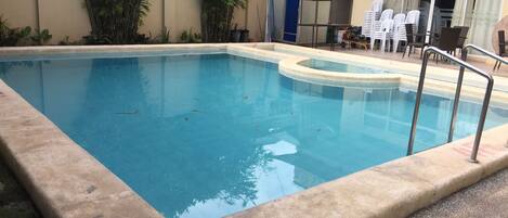 A rectangular pool with a concrete edge, surrounded by a concrete deck.