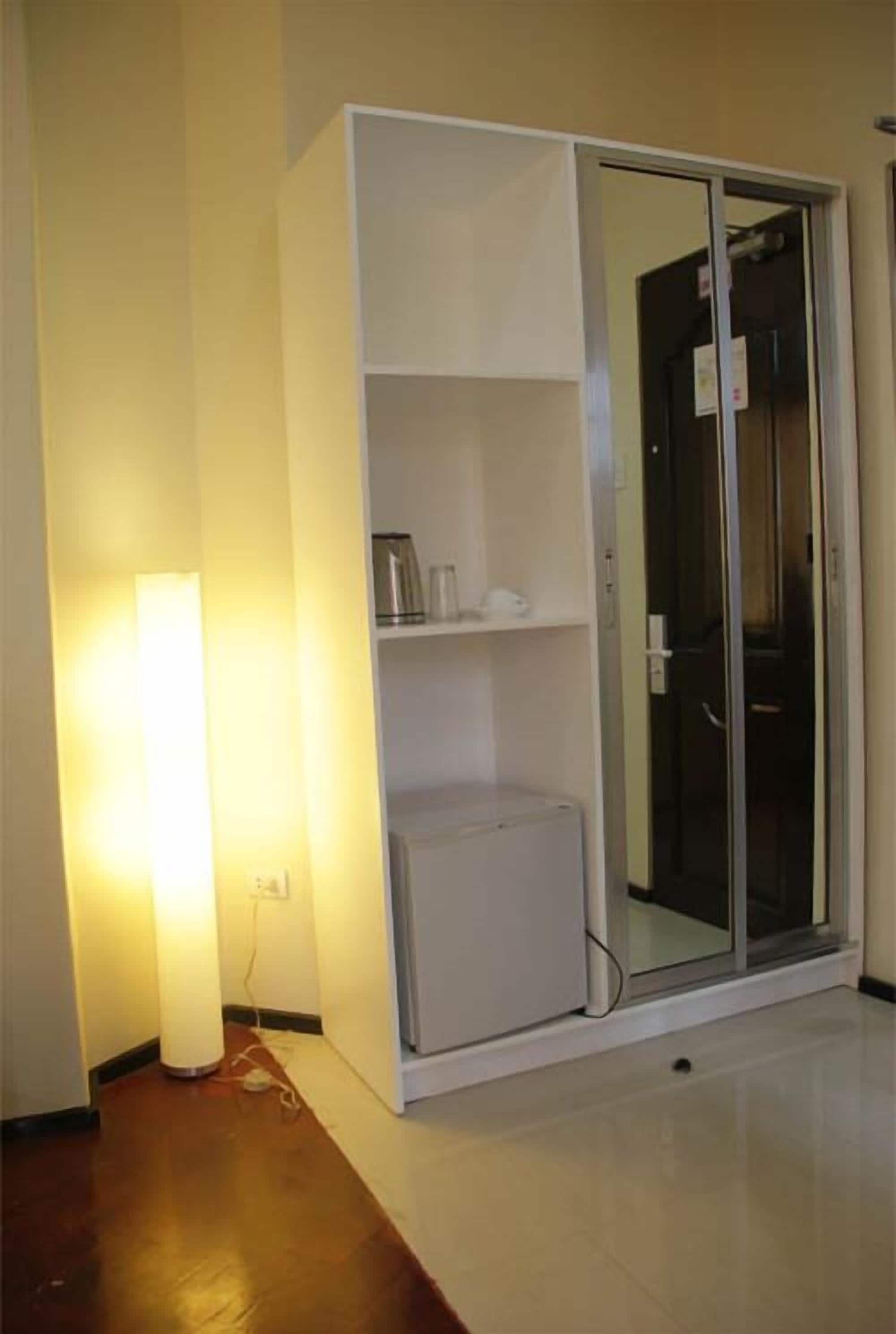 A room with a white wardrobe, a small heater, and a glass door leading to another room.