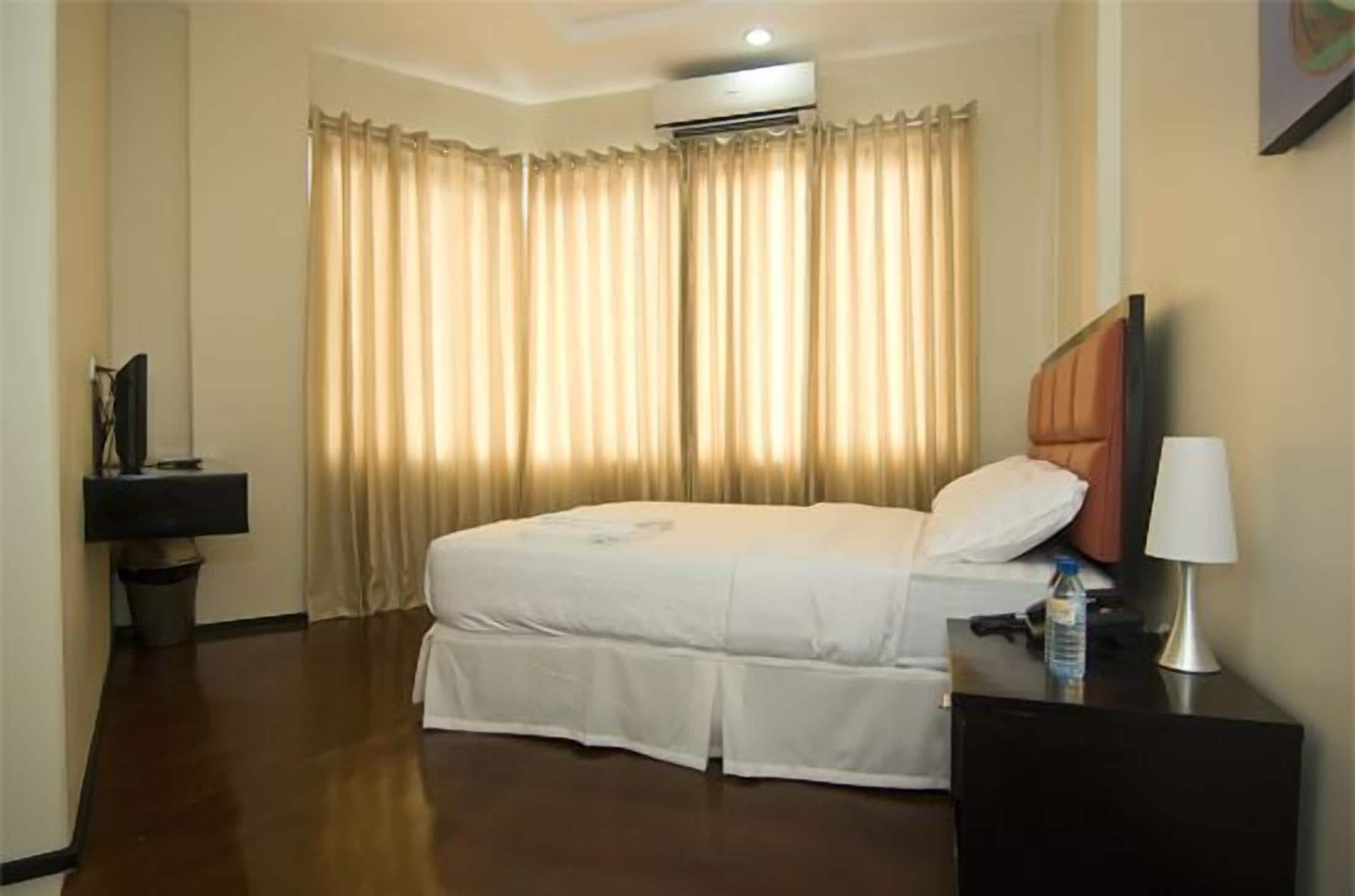 A hotel room with a bed, a nightstand, a lamp, and a TV.