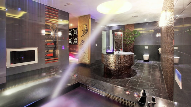 Un baño moderno con un lavamanos central, suelo con calefacción y un panel decorativo en la pared.