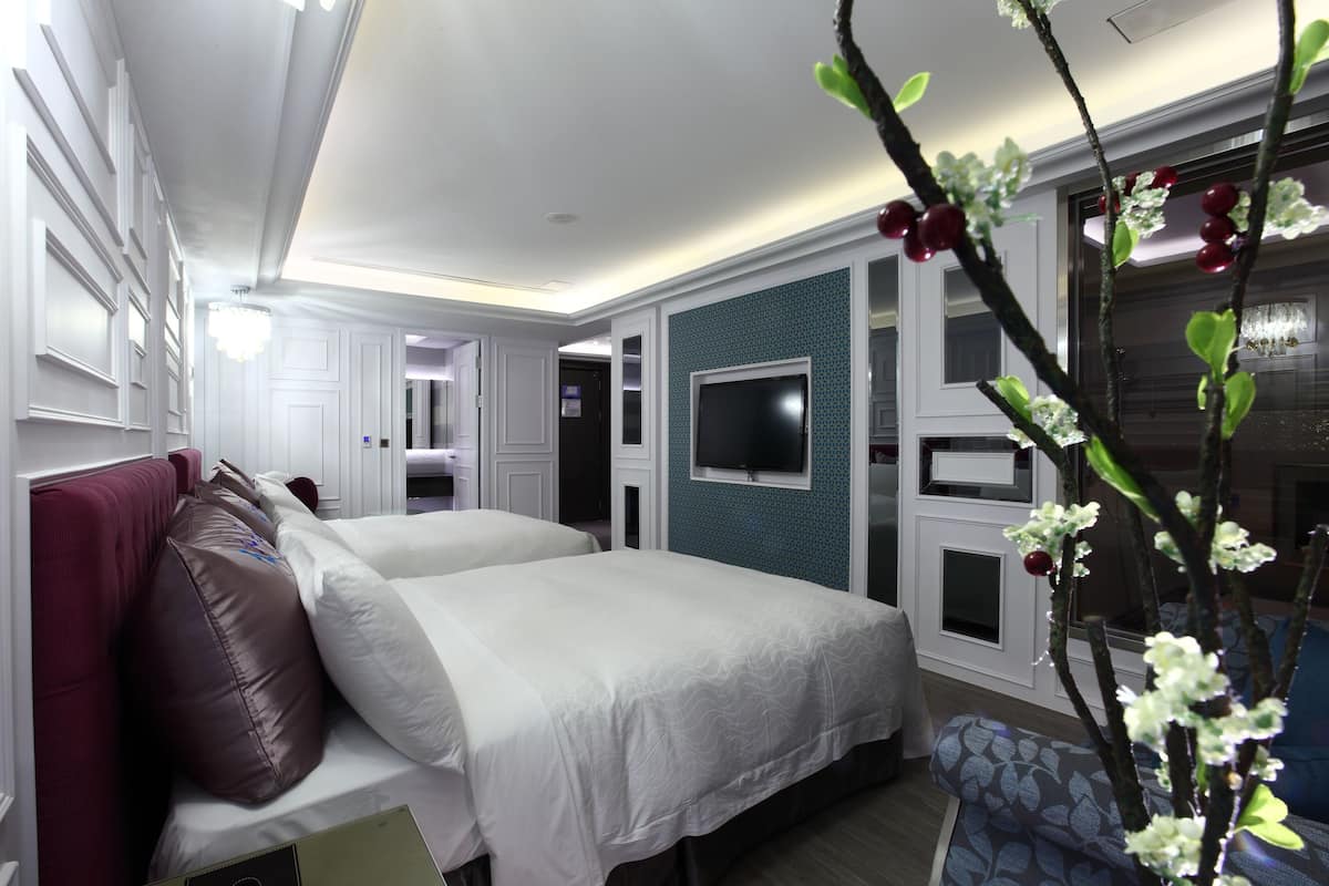 Une chambre d’hôtel comprenant un lit, un coin salon, un téléviseur fixé au mur et une plante décorative.