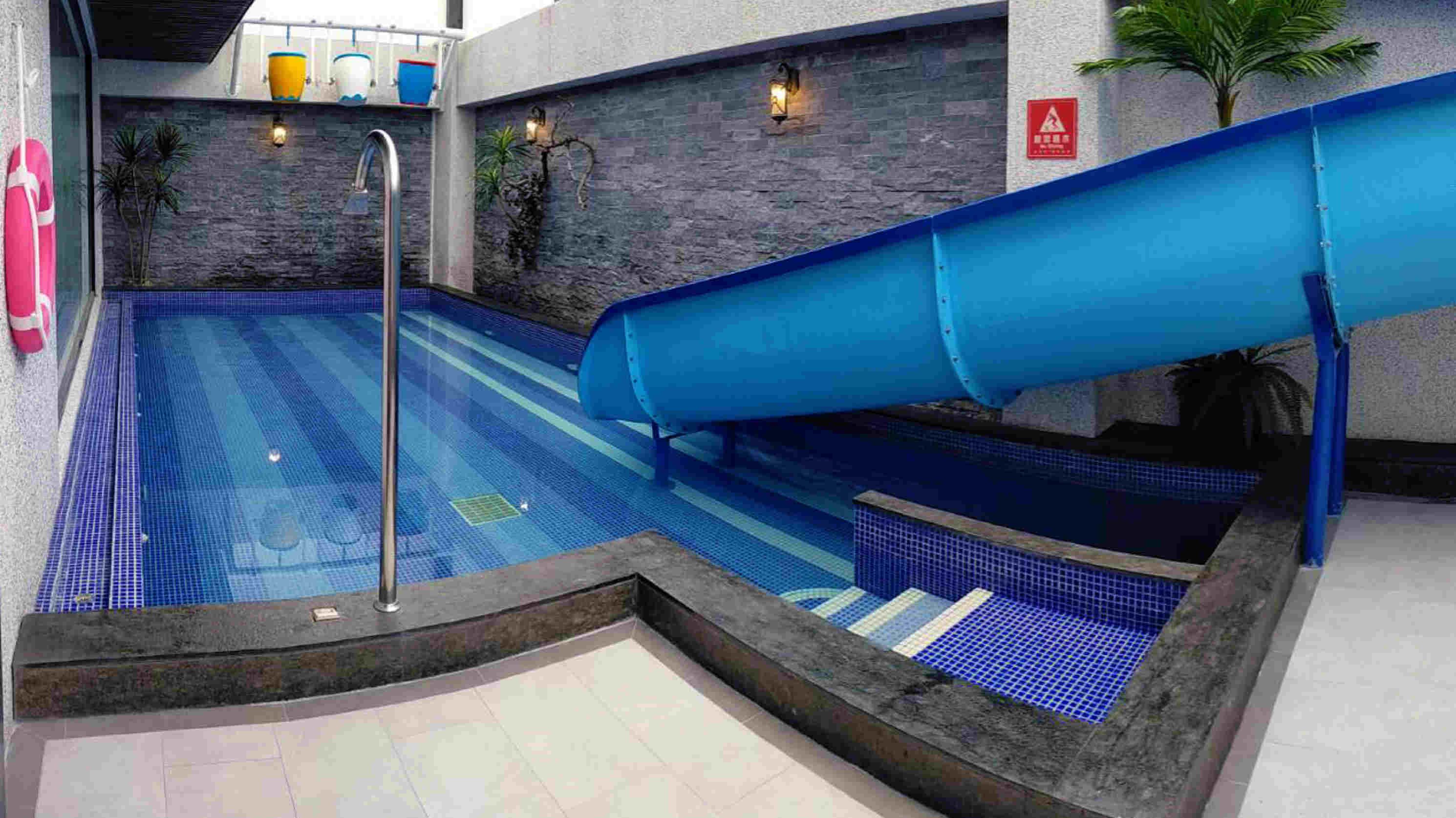 Una piscina con un tobogán azul, una fuente de agua y un cartel de seguridad.