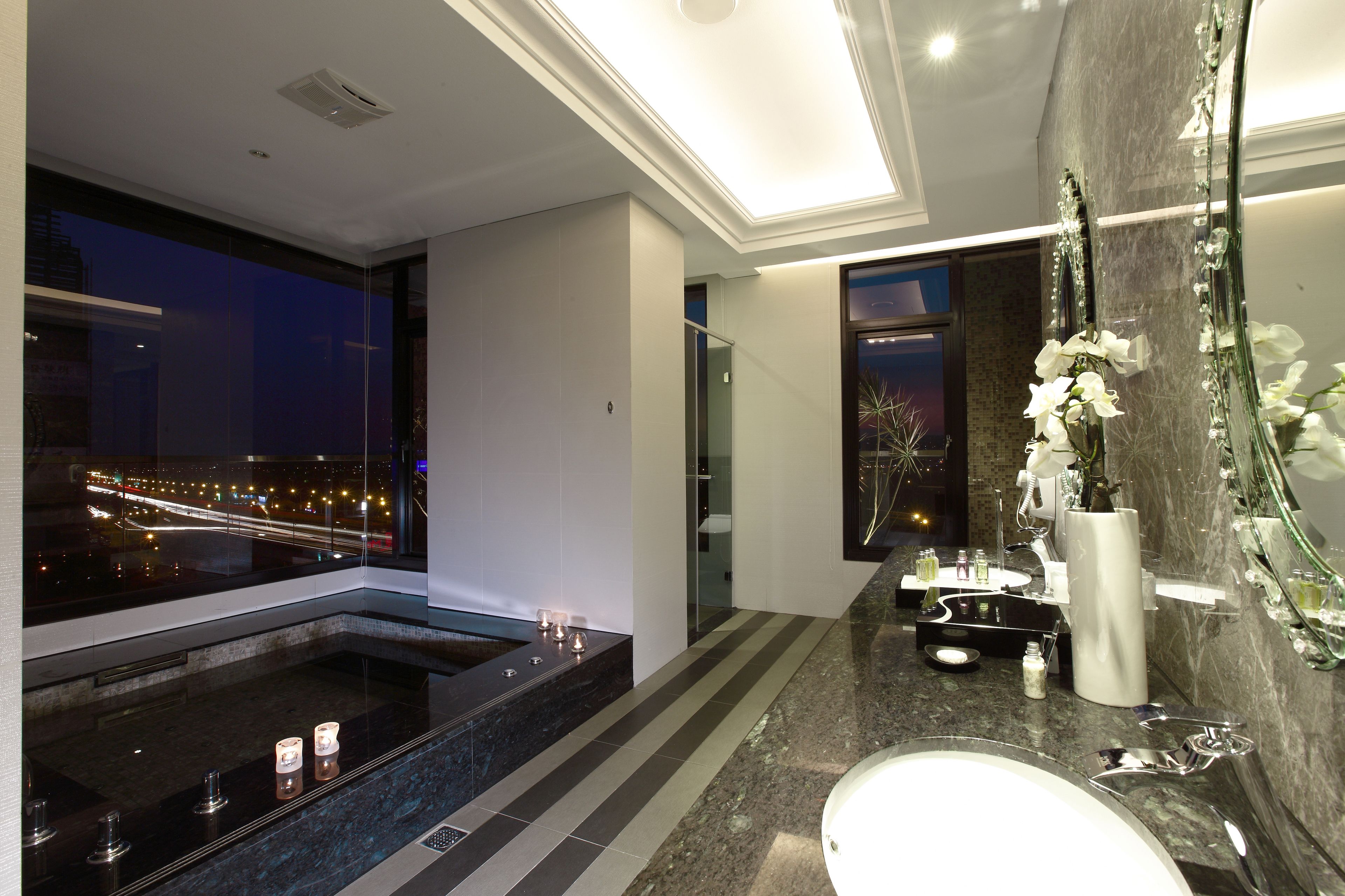 A modern bathroom with a large bathtub, a sink, and a mirror.