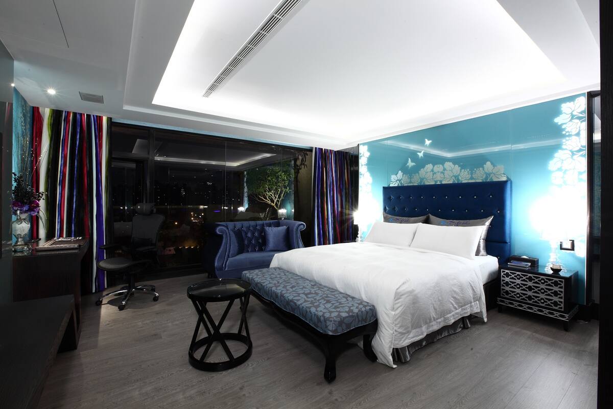 Une chambre à coucher moderne avec un grand lit, un banc, un bureau et une chaise.