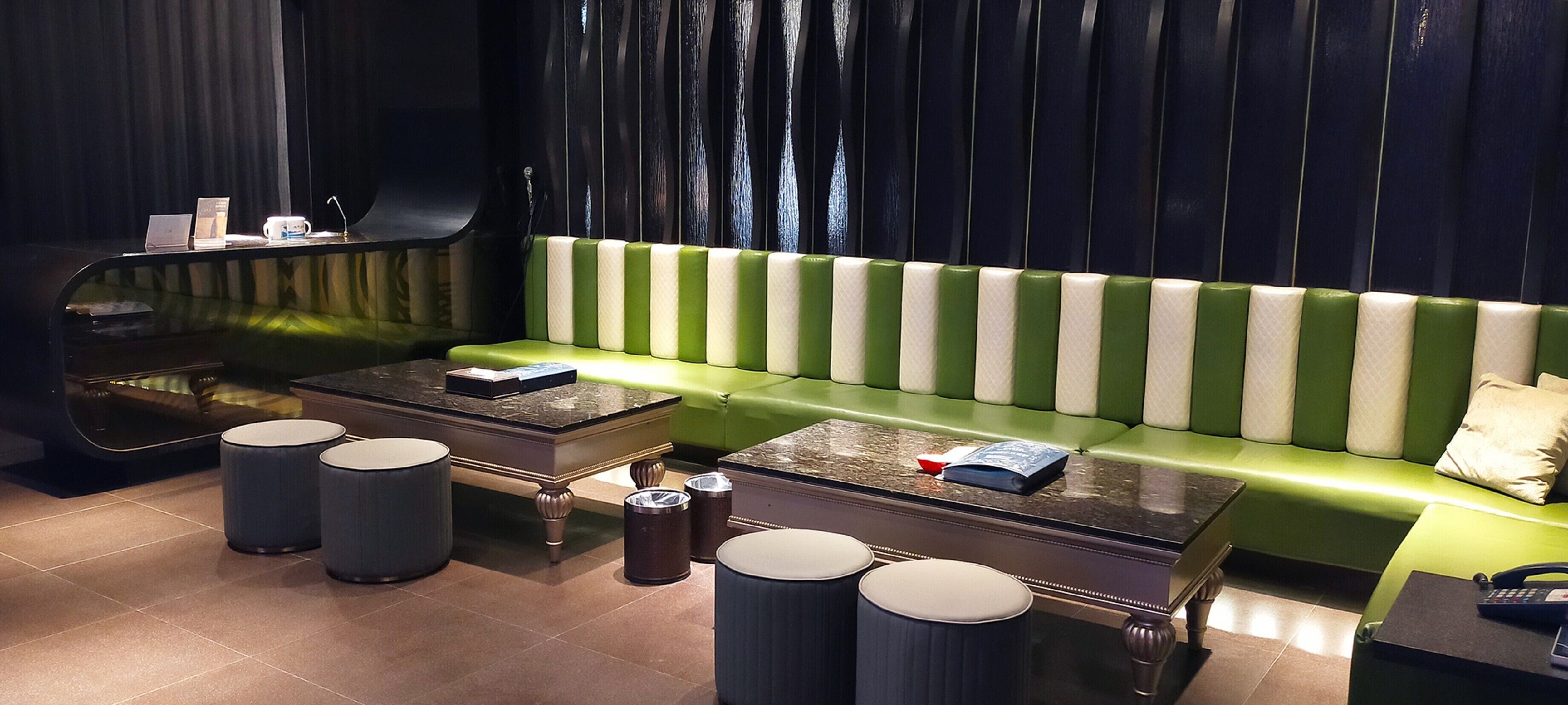 A modern lounge area with a green sofa, a marble coffee table, and a black telephone.