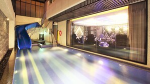 Un tobogán interior moderno con recinto de cristal, una escalera y vistas a una habitación con decoración estampada.