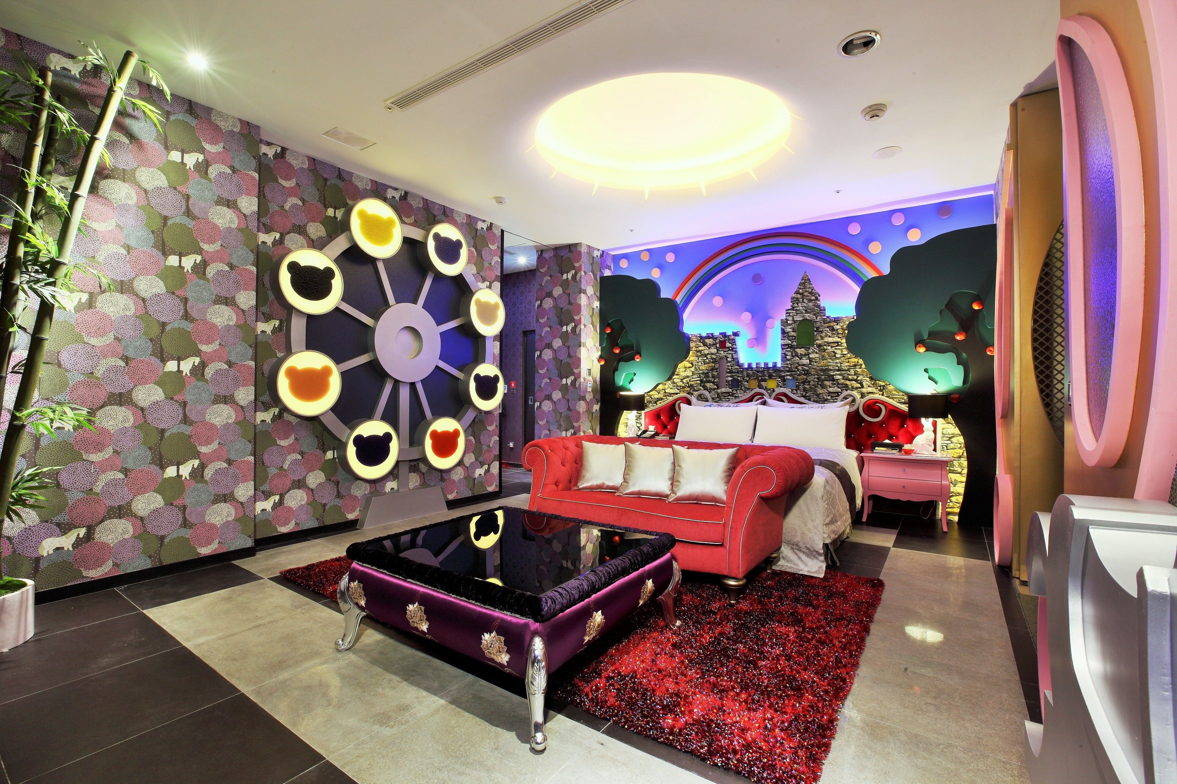 A modern living room with a red sofa, a glass coffee table, and a decorative wall with circular patterns.