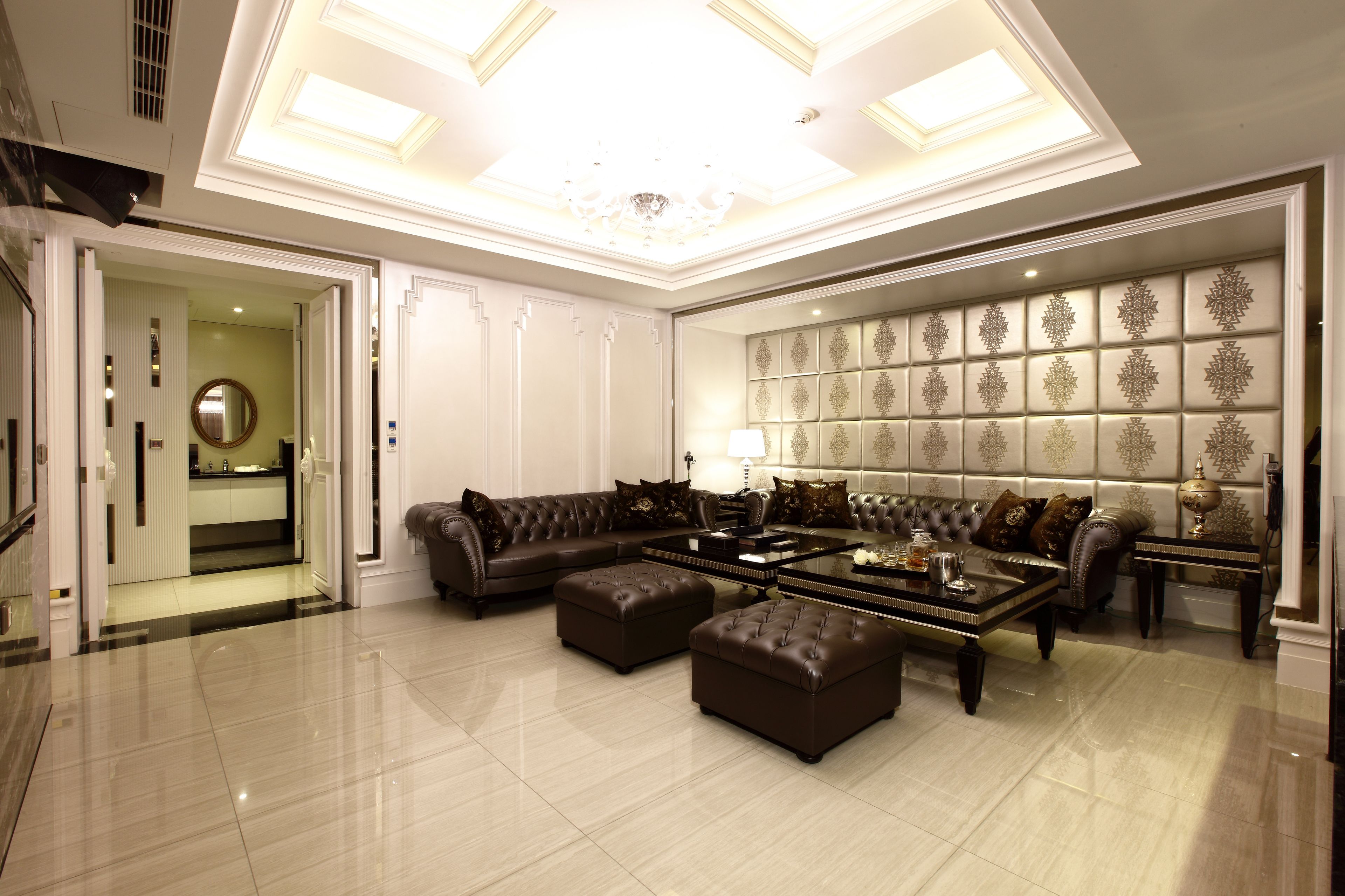 A spacious living room with a large sectional sofa, two ottomans, a coffee table, and a patterned wall.