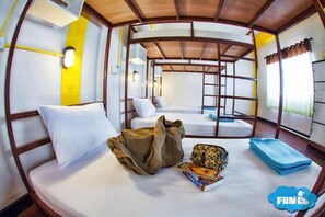 A bunk bed room with a wooden ceiling, a small table with a book and a bag, and a window with curtains. - FUN-D Hostel Chiang rai (Chiang Rai)