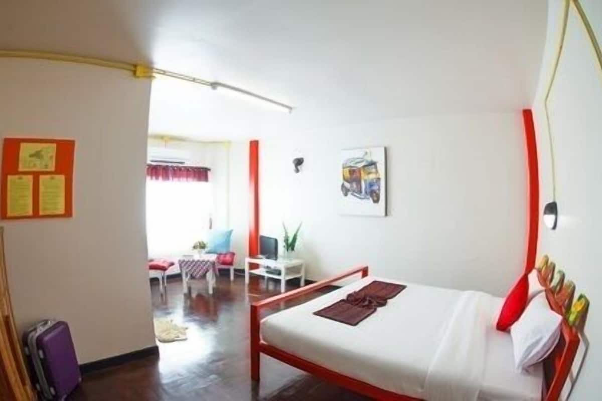 A room with a bed, a desk, and a chair. There is a suitcase on the floor.