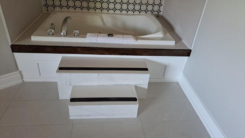 Un baño con bañera, lavamanos y tocador con cajones.