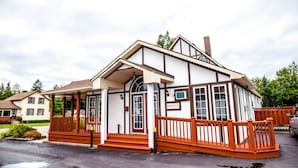 A two-story building with a porch, a sign indicating an office, and a brick chimney. - Cedar Lodge Motel (Goderich)
