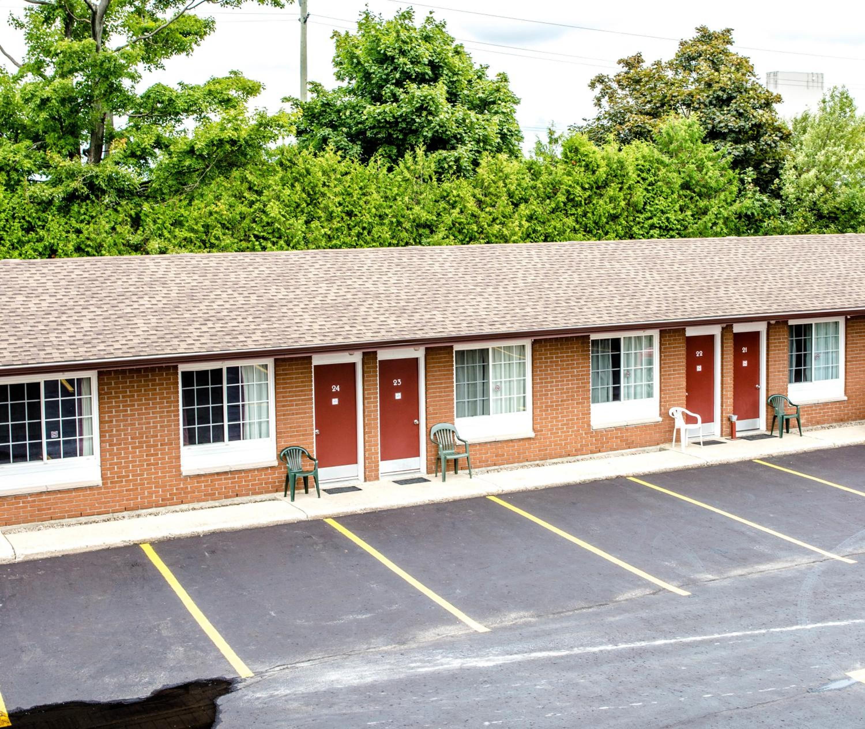 A motel with a row of rooms, each with a door and window, and a parking lot in front.