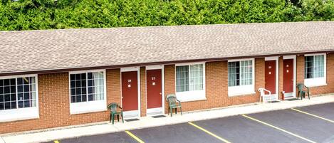 A motel with a row of rooms, each with a door and window, and a parking lot in front.