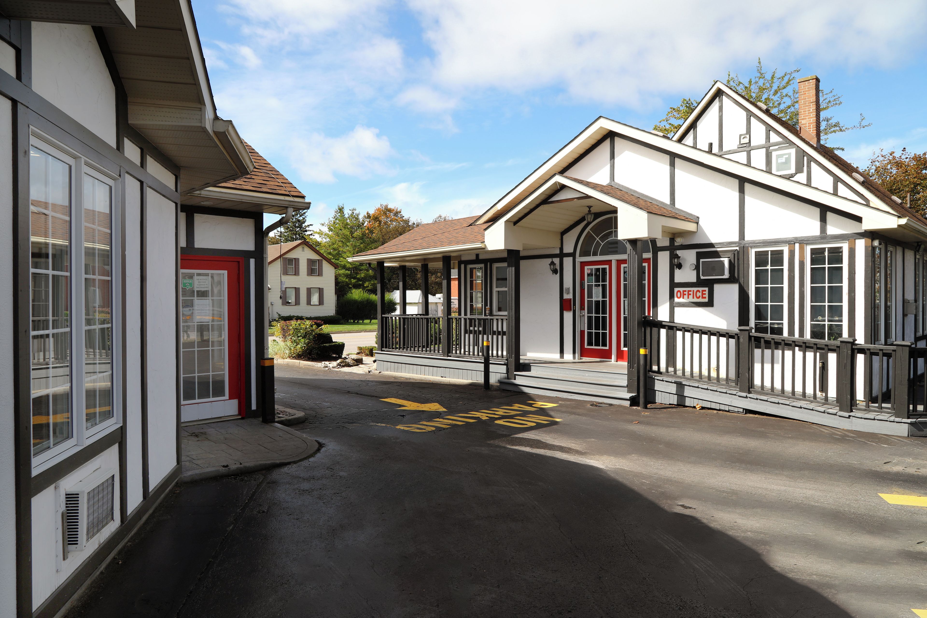 A building with a red door, a sign reading 'OFFICE', and a yellow arrow on the pavement.