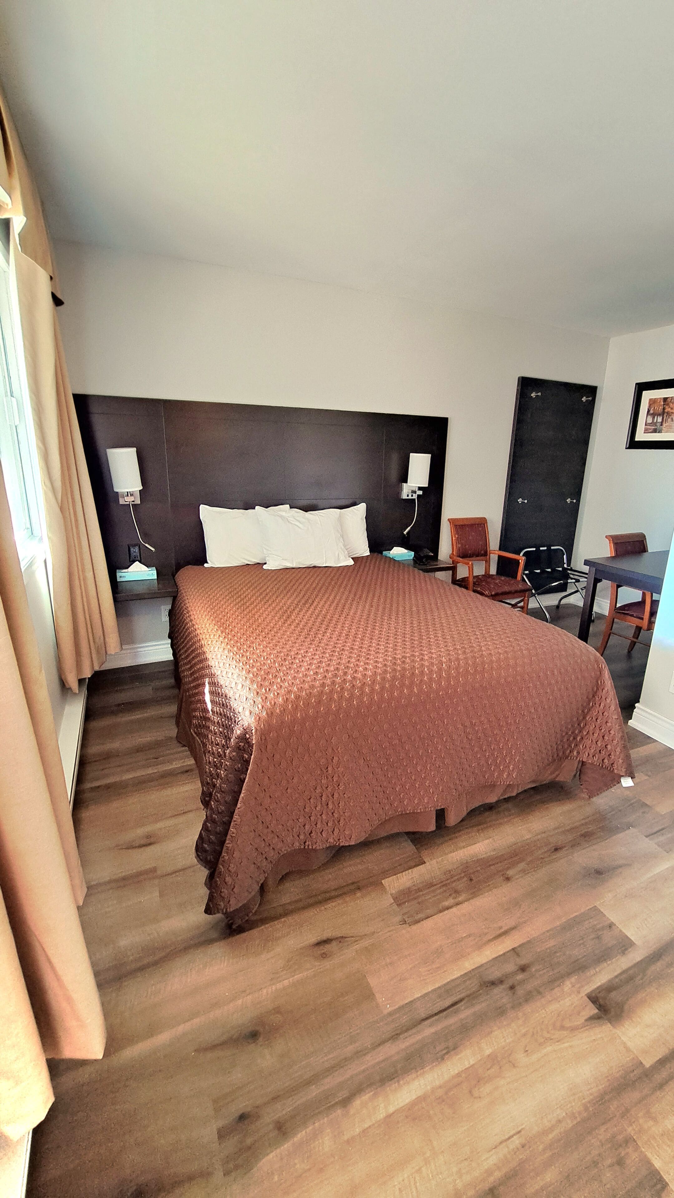 Ein Hotelzimmer mit einem großen Bett, einem Schreibtisch, einem Stuhl und einer Tür.
