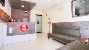 Un espace d’accueil comprenant un canapé, un comptoir de réception et une horloge murale.