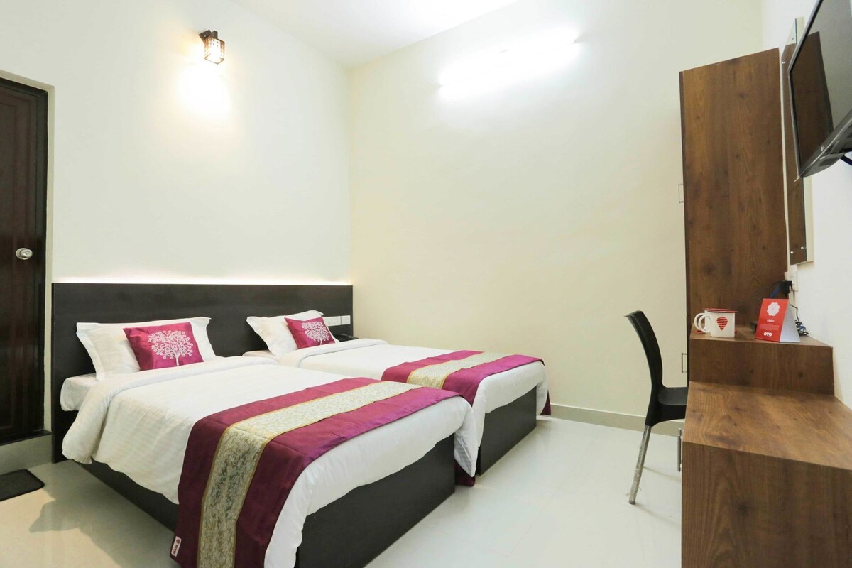Une chambre d’hôtel avec deux lits, un bureau, une chaise et un téléviseur.