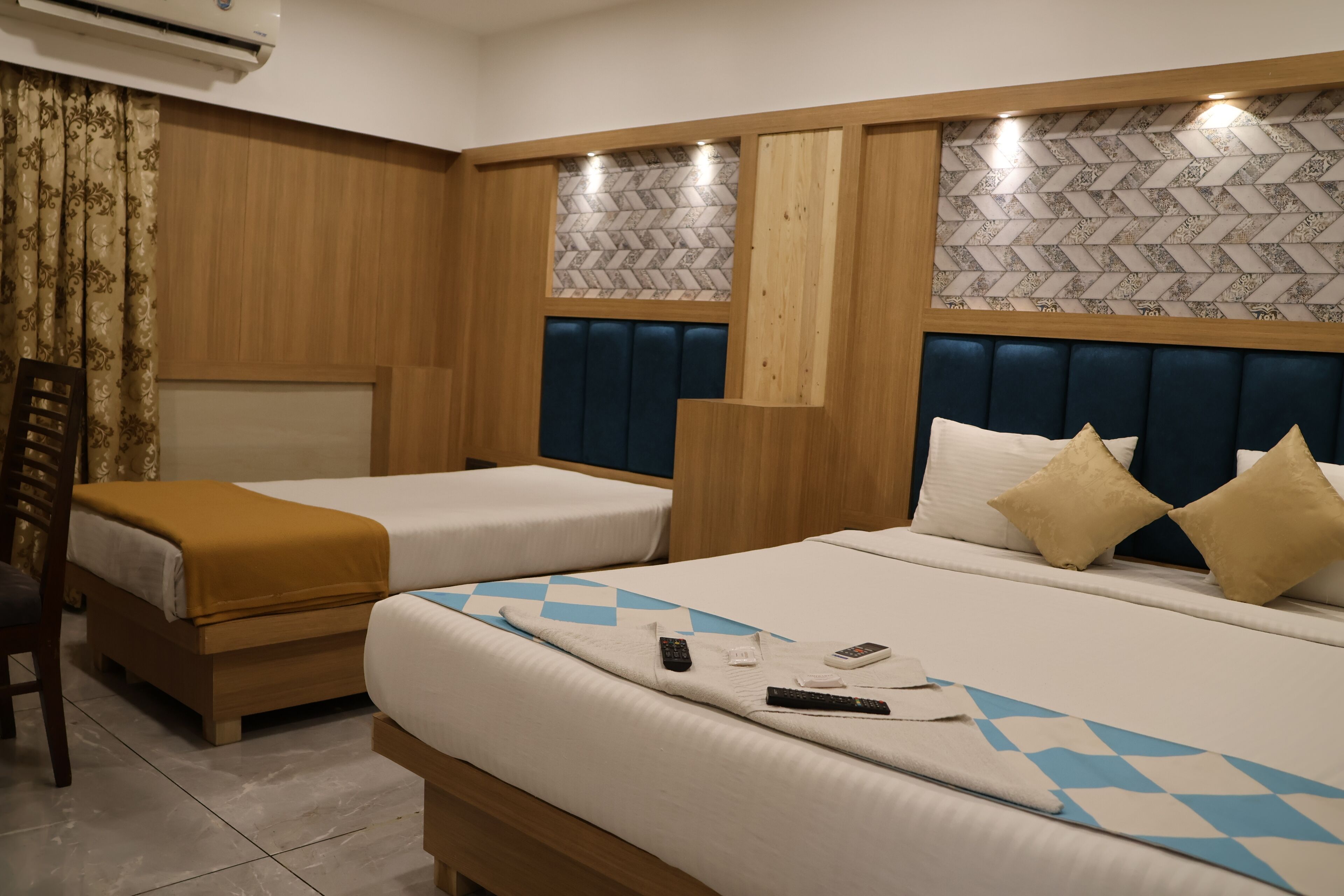Camera d'albergo con due letti, una testiera in legno, una parete decorata e una tenda.