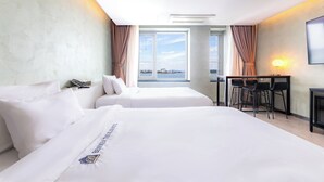A hotel room with two beds, a desk with chairs, a large window with curtains, and a wall-mounted lamp. - Benikea The Bliss Hotel (Incheon)