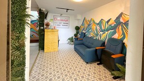Una zona de recepción con un sofá, un escritorio y un mural colorido.