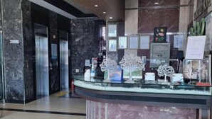 Un mostrador de recepción con un cartel que dice "INFORMATION" en un vestíbulo moderno con suelo de mármol y una barra de cristal.