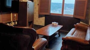 Una habitación con piso de madera, un televisor en la pared, una mesa de madera y dos sofás de cuero.