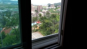 Vista desde una ventana que da a una zona residencial con edificios, árboles y cielo despejado.