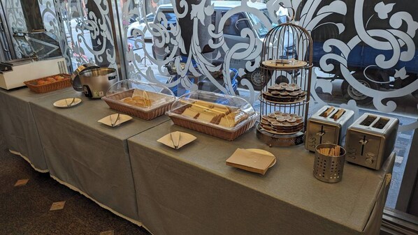 A buffet setup with various food items and utensils on a table, with decorative metalwork in the background. - Waugh Den Hotel (Taichung)