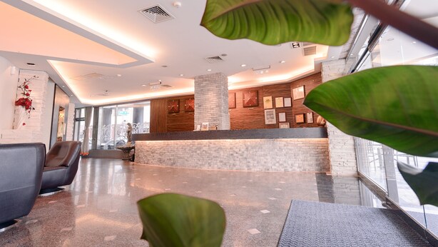 A modern lobby with a reception desk, seating area, and large windows. - Waugh Den Hotel (Taichung)