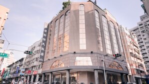 A multi-story hotel with a curved facade, large windows, and a prominent entrance with a covered area. - Waugh Den Hotel (Taichung)