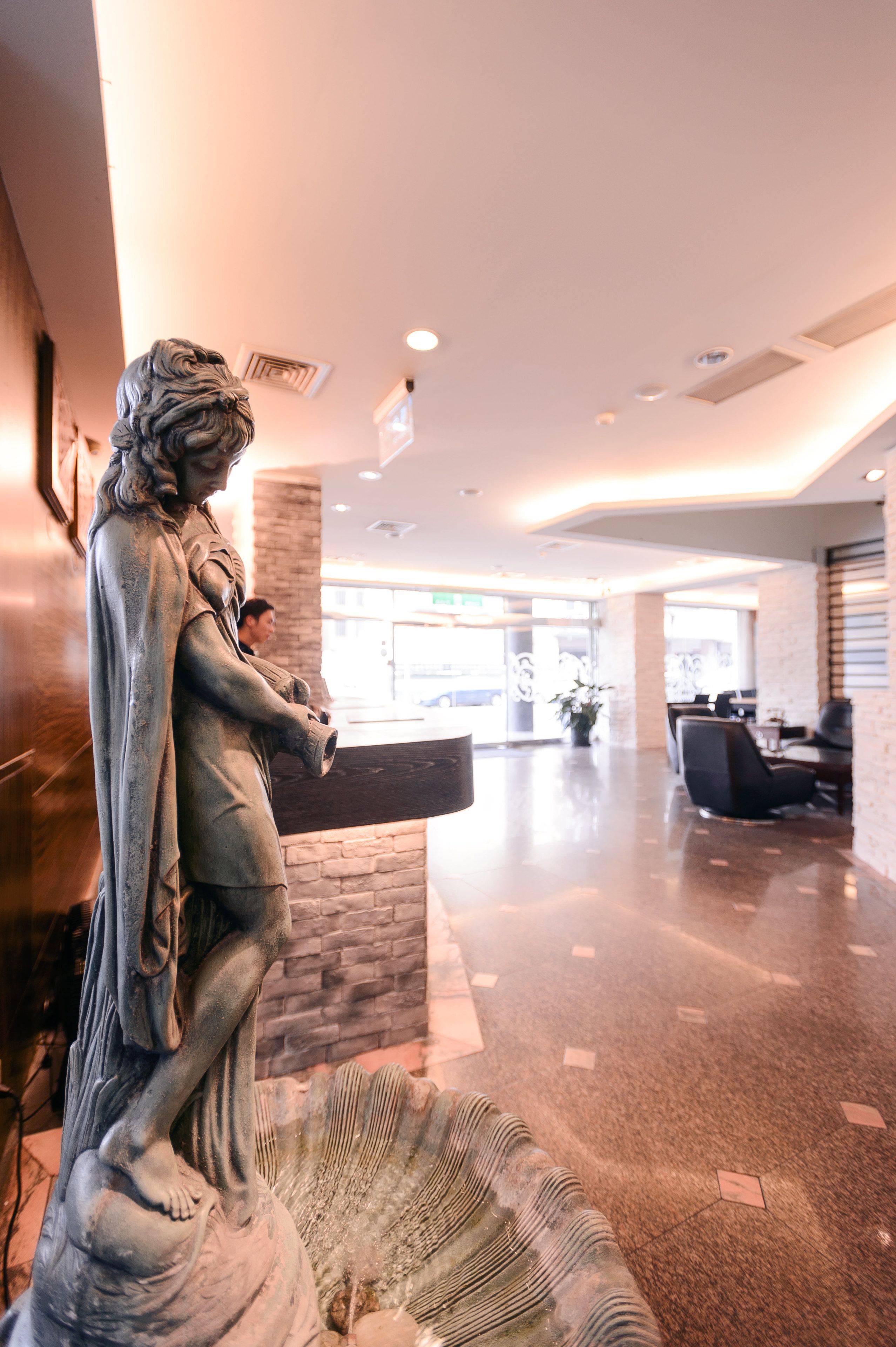 A statue in a lobby with a reception desk and seating area.