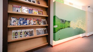 A wall with a green landscape mural and a sign with arrows. - Waugh Den Hotel (Taichung)