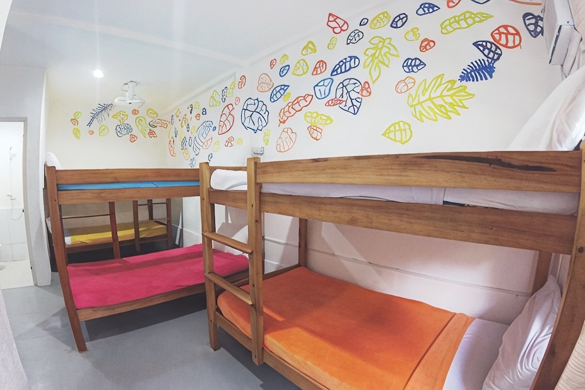 A bunk bed room with a wall mural of various leaf patterns.