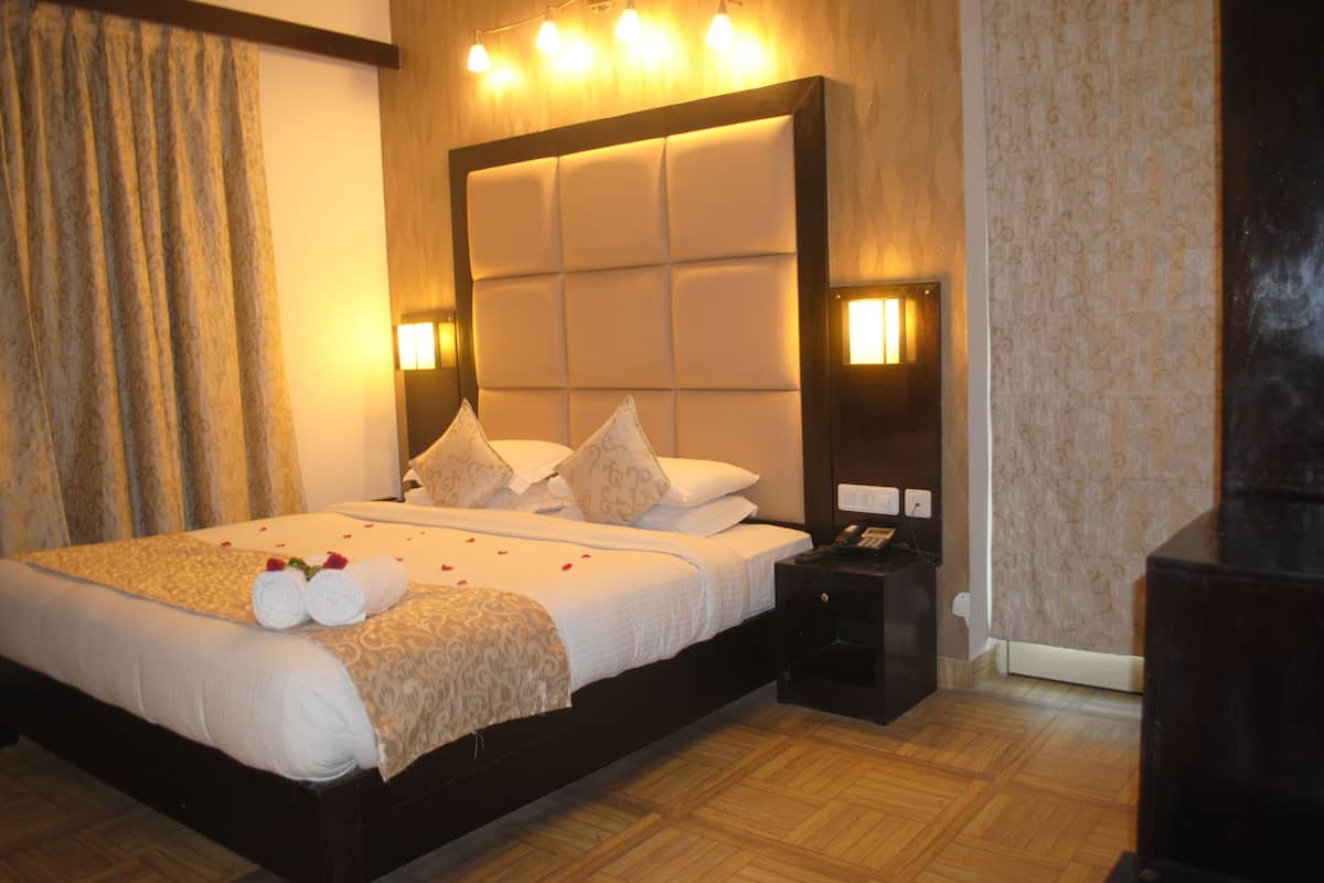 Une chambre d’hôtel avec un grand lit, une table de chevet et une commode.
