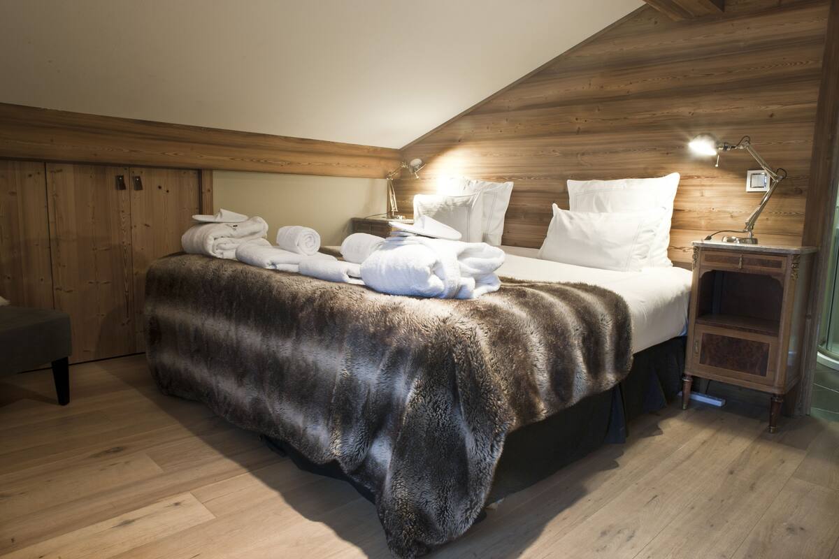 Ein Zimmer mit einem Bett, Holzwänden, einem Nachttisch mit Lampe und einer Bank.