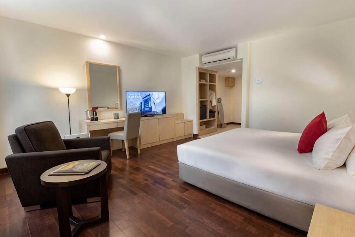A hotel room with a bed, a desk, a chair, a television, and a wardrobe.