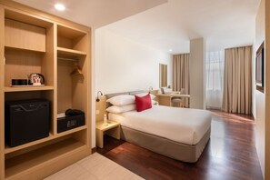 A hotel room with a bed, a desk, a wardrobe, and a mirror.