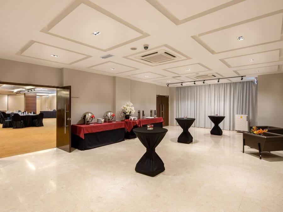 A spacious conference room with a long table, black round tables, and a seating area with a sofa.