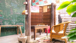 A rustic outdoor seating area with a wooden table and chairs, a chalkboard with writings, and a brick pathway. - Smalleye Backpacker (Lukang)