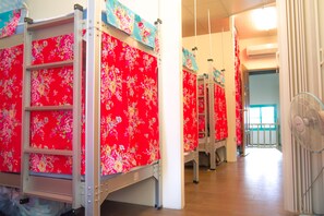 A hotel corridor with rows of beds, each with a red floral headboard. - Smalleye Backpacker (Lukang)