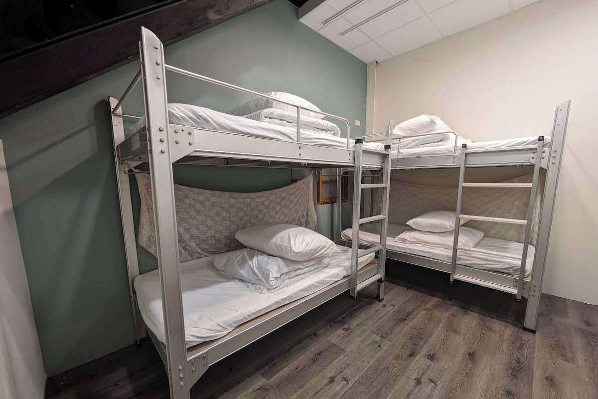 A bunk bed room with metal frames and white bedding.