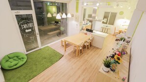 Un interior luminoso y moderno con una mesa de comedor de madera, sillas y un asiento con cojín verde.
